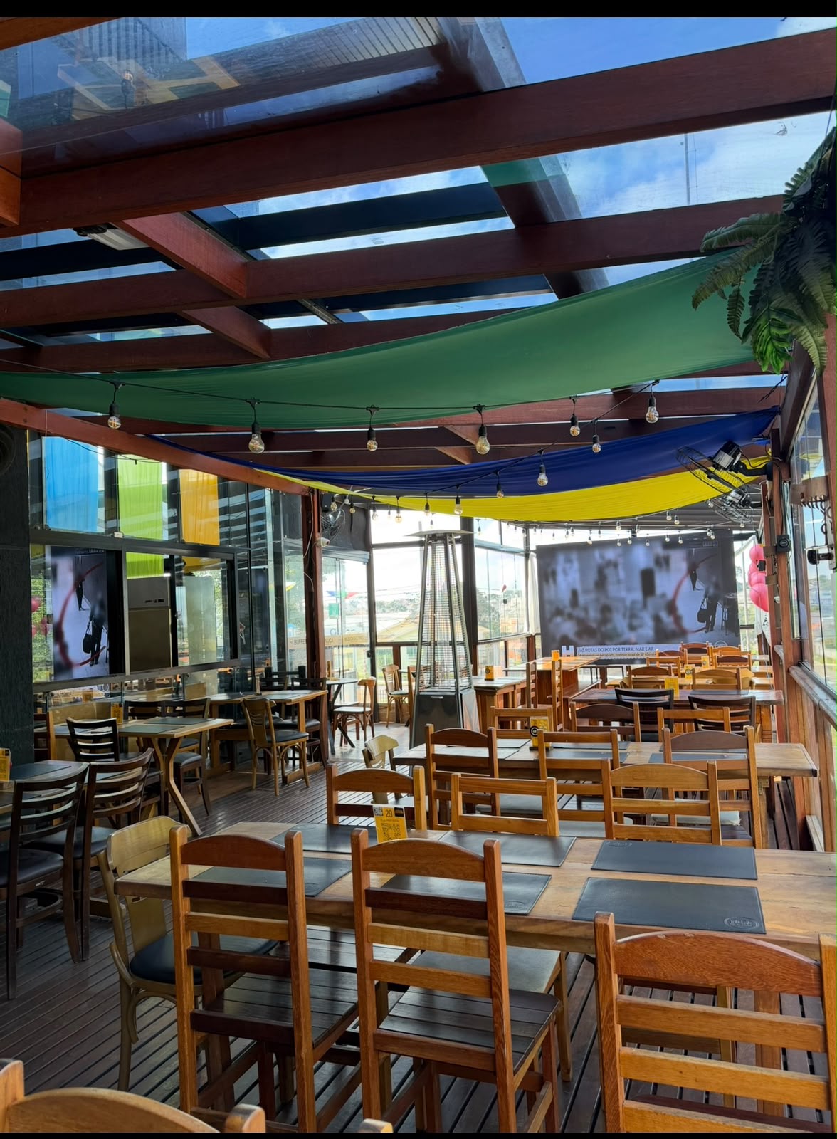 Ambiente interno do Tora Bar com mesas e cobertura de vidro